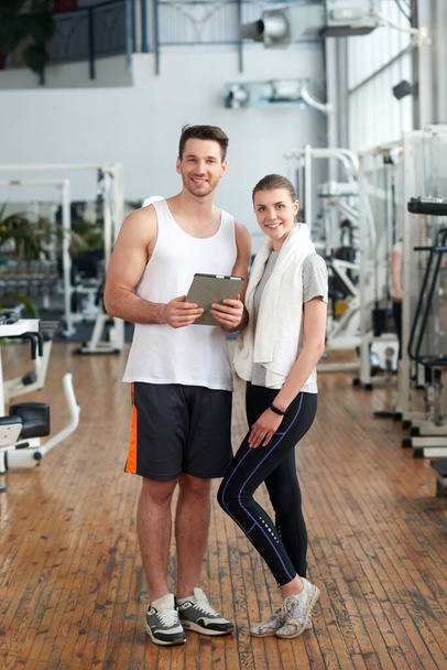 Jeune couple sportif regardant la caméra dans la salle de gym. - Photo, image