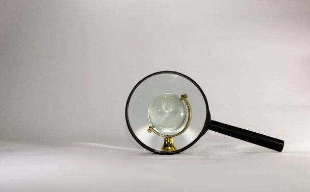 κρυστάλλινη σφαίρα δείτε μέσα από μεγεθυντικό φακό σε λευκό φόντο - Φωτογραφία, εικόνα