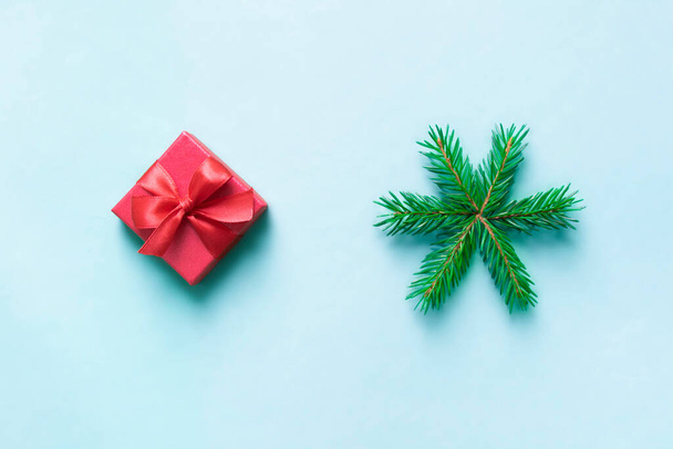 on a blue background a red gift with a bow and a snowflake from fir branches. - Foto, Imagen