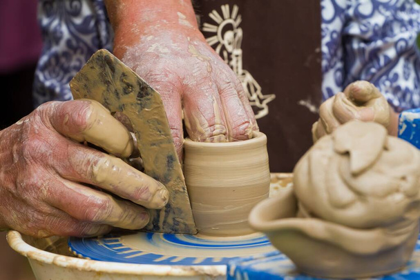 ügyes kézműves kezek alkotnak agyagtálat a hagyományos kerámia keréken, néprajzi tanulmány készítése a hagyományos ökológiai konyhai termékek, mozgás elmosódás hatása - Fotó, kép