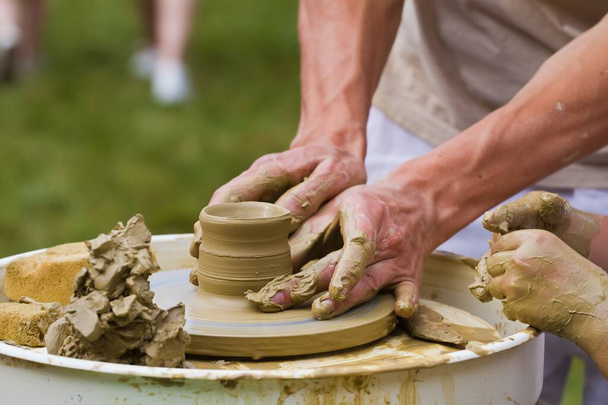 hábil artesano manos forman un tazón de arcilla en una rueda de cerámica tradicional, estudio etnográfico en la fabricación de productos de cocina ecológicos tradicionales, efecto de desenfoque de movimiento - Foto, imagen