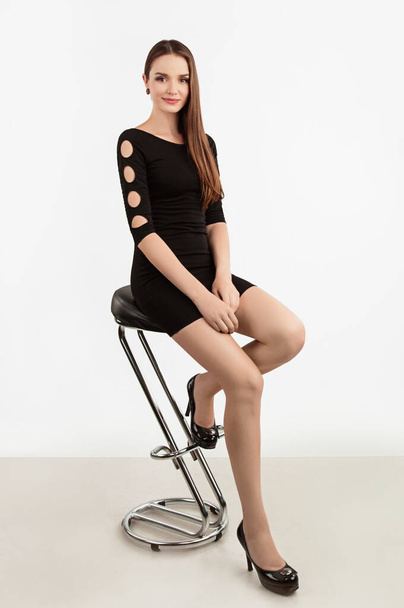 Portrait of a beautiful happy girl with different emotions in a black dress and shoes in the studio on an isolated background - Foto, afbeelding