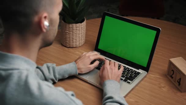 Homem caucasiano jovem usando uma tela verde Laptop na mesa em casa. - Filmagem, Vídeo