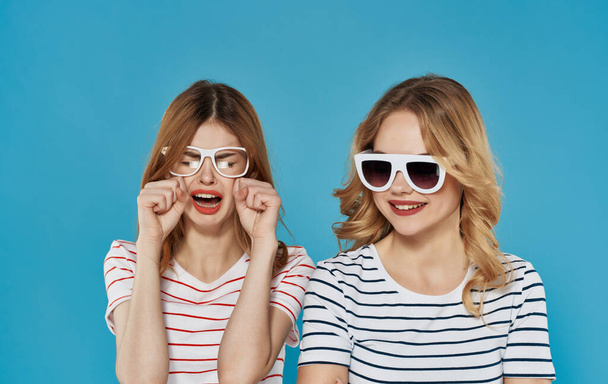 Симпатичные девушки в полосатых футболках темные очки моды коммуникации синий фон - Фото, изображение
