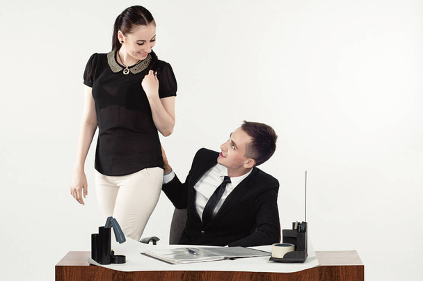 Beautiful and young. A businessman sexually harasses a businesswoman at an office desk and gives her money. White isolated background. - Foto, Imagen