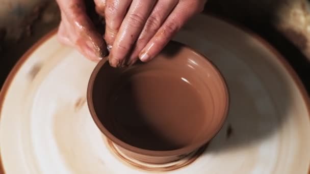 handen werken klei op pottenbakkerswiel. Pottenbakker vormt het klei product met aardewerk gereedschap op het pottenbakkerswiel, ambachtelijke fabriek authentiek. Sluit maar af. 4k - Video