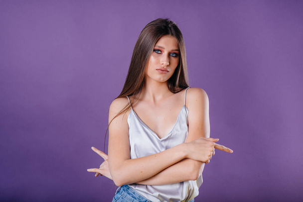 A young beautiful girl shows emotions and smiles in the Studio on a purple background. Girls for advertising - Foto, Bild