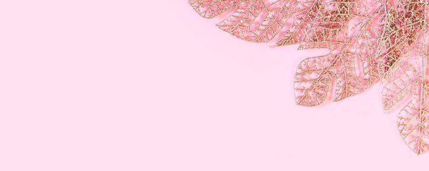 Goldene künstliche Blätter auf rosa Hintergrund mit Kopierraum für Text. Minimaler Stil. Flach lag er. Schöne Feier-Kulisse. - Foto, Bild