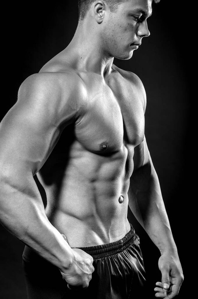 Sexy young athlete posing on a black background in the Studio. Fitness, bodybuilding, black and white - Foto, Bild