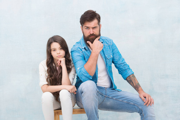 Family of cute girl child with beauty look and bearded brutal man in casual fashion style sit on stool, serious - Foto, Imagen