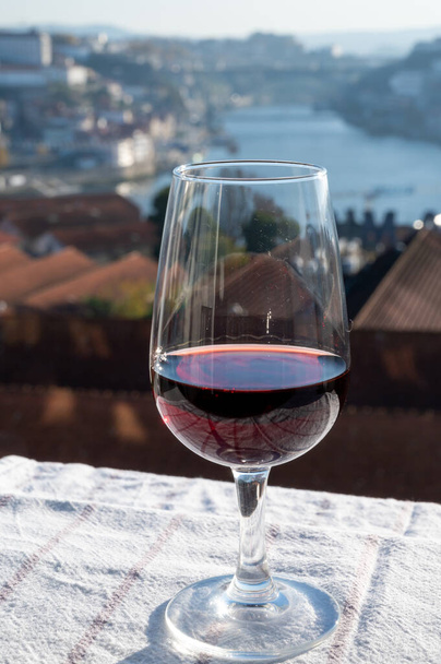 Tasting of different fortified dessert ruby, tawny port wines in glasses with view on Douro river, porto lodges of Vila Nova de Gaia and city of Porto, Portugal, close up - Photo, Image