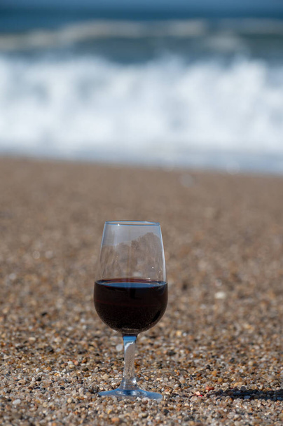 Maistelua eri väkevöity jälkiruoka rubiini, tawny portviini lasi hiekkarannalla näköalalla Atlantin valtameren aallot lähellä Vila Nova de Gaia ja kaupungin Porto, Portugali - Valokuva, kuva
