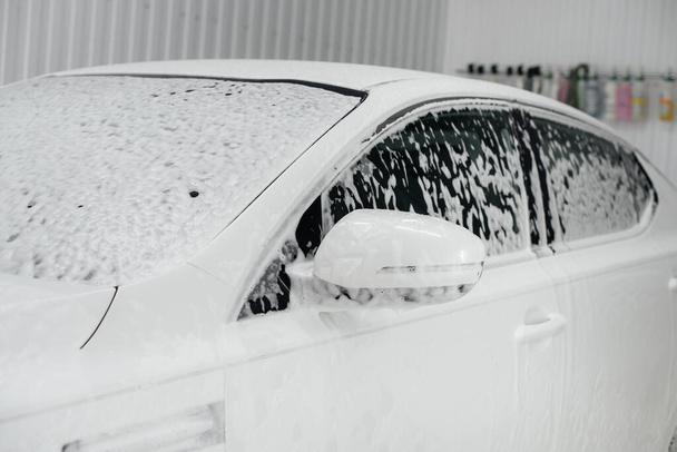 Modern washing with foam and high-pressure water of a white car. Car wash - Fotografie, Obrázek