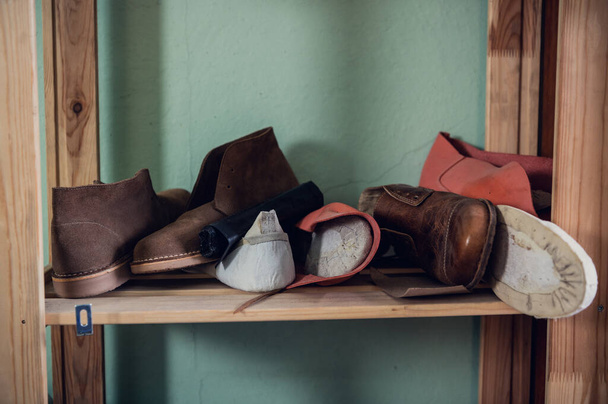 Étagère en bois avec différentes chaussures avec des blancs pour les chaussures dans l'atelier - Photo, image