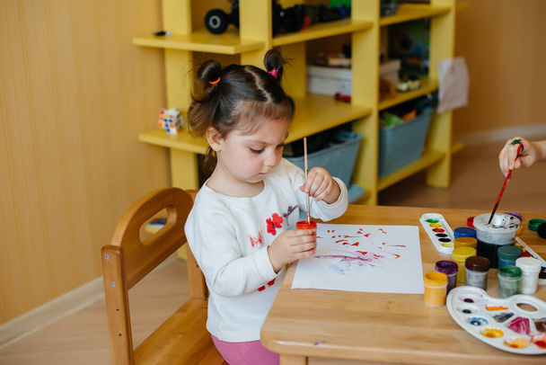 A cute little girl is playing and painting in her room. Recreation and entertainment - Fotó, kép