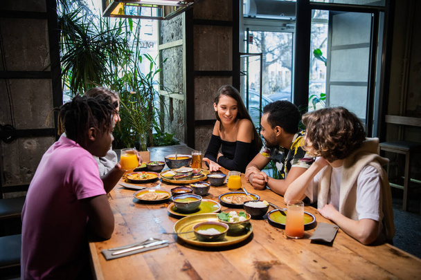 カフェでアジア料理を食べながら多文化の若者たち - 写真・画像