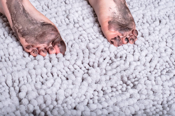 Gros plan des pieds nus sales de l'enfant sur tapis gris. Photo de haute qualité - Photo, image