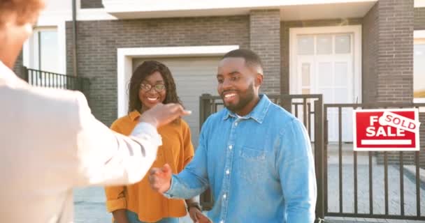 Rear of real-estate selling house to African American happy couple and handing keys. Outdoor. Joyful married man and woman hugging and buying home at outskirt. Getting dwelling in suburb. back view. - 映像、動画