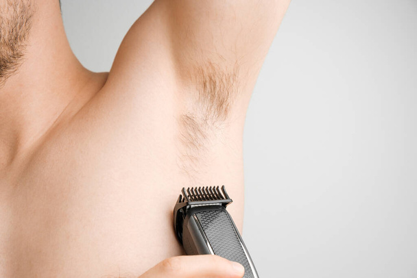 Close up uomo radere le ascelle pelose con un rasoio elettrico. Ascelle non rasate o ascelle. Depilazione e rimozione dei capelli con trimmer. Corpo vergognoso concetto - Foto, immagini