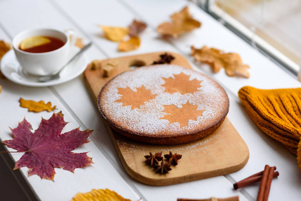 Bella torta di zucca dolce fresca con un modello di foglia d'acero su uno sfondo di legno bianco con una composizione di foglie autunnali secche - Foto, immagini