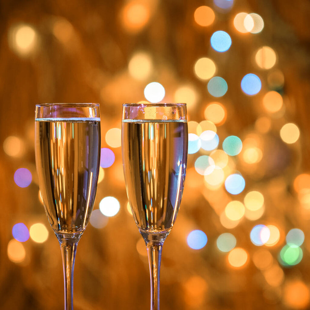 Champagne glass close up on Christmas and New Year holiday bokeh background. Two glasses with bubbly tasty sparkling drink. Happy New Year! Celebrating winter holidays, 4K, close up, macro - Fotoğraf, Görsel