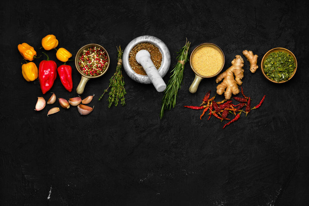 Composition with mixture of peppers, ginger, garlic, thyme, chilli and rosemary on dark background - Foto, Imagem
