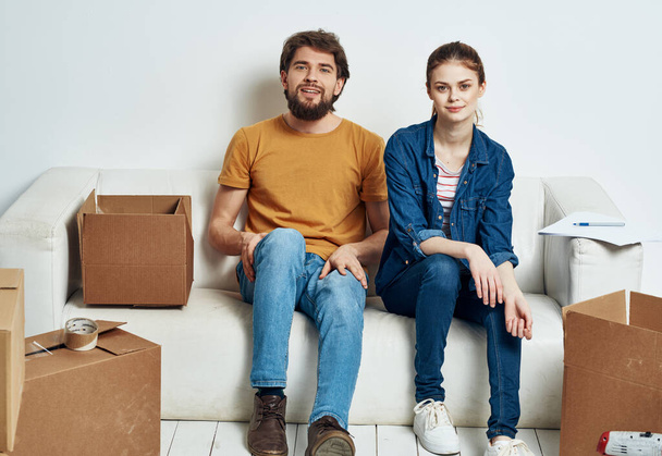 Мужчина и женщина сидят на диване с коробками с инструментами, двигающими интерьер - Фото, изображение