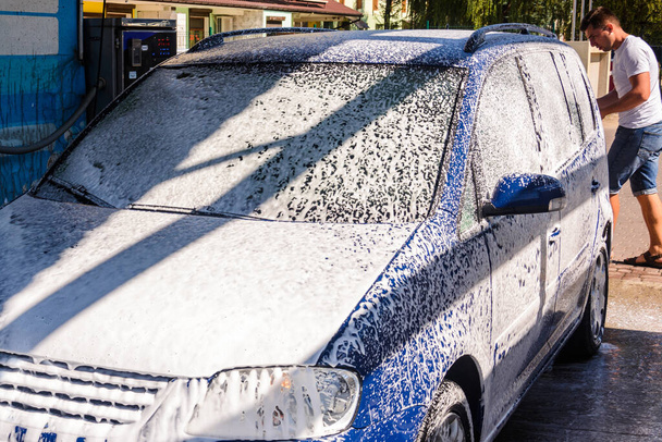 Car wash, een persoon bij een self-service car wash, onder druk zet schuim op de auto.2020 - Foto, afbeelding