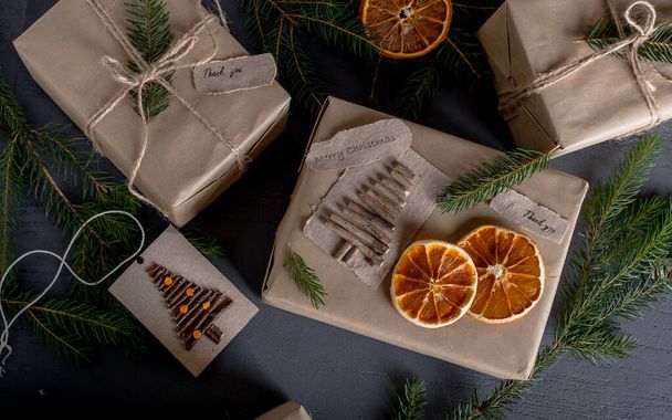 Weihnachten und Null Abfall, umweltfreundliche Verpackungsgeschenke in Kraftpapier, getrocknete Orangen, Weihnachtsbaumzweige. Öko-Weihnachtsurlaub Konzepte, Öko-Dekor. Hochwertiges Foto - Foto, Bild
