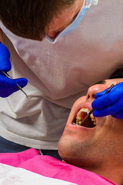 Bezoek aan de tandarts, de tandarts evalueert de mondholte en identificeert probleemgebieden van de tand.2020 - Foto, afbeelding