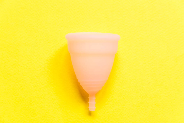 Coupe menstruelle rose design tout simplement minime Isolé sur fond jaune. Femme alternative moderne hygiène éco gynécologique dans la période de menstruation. Conteneur pour sang. Espace de copie de vue de dessus plat - Photo, image
