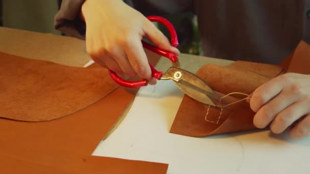 Een ervaren leerlooier in het proces van het maken van een dameshandtas. Snijdt de overtollige sartoriale draad af en verzegelt de punt met een aansteker. - Video