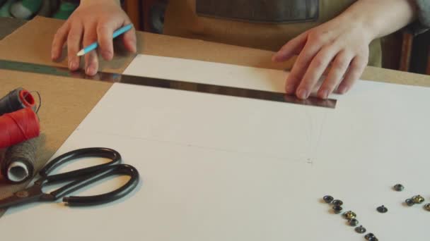 Ένας ράφτης σημειώνει ένα φύλλο χαρτιού με ένα μολύβι για την κατασκευή προτύπων των συγγραφέων παπούτσια για μια οικογενειακή επιχείρηση. - Πλάνα, βίντεο