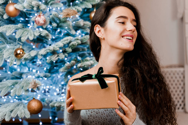 Kız için Noel hediyesi. Yılbaşı ağacının yanında güzel bir kadın. Çevrimiçi Mağazalar İçin Yeni Yıl Satışları - Fotoğraf, Görsel