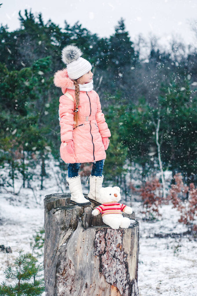Смішна дівчинка взимку засніжений новорічний ліс грає з іграшковим білим ведмедем. Зимовий портрет дитини
. - Фото, зображення