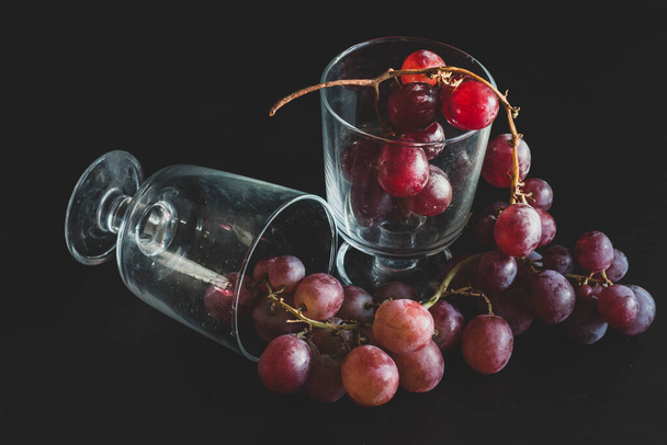 Red grapes, large bunch of fruits, fresh and tasty simple food on a dark background in a fancy minimal composition - 写真・画像