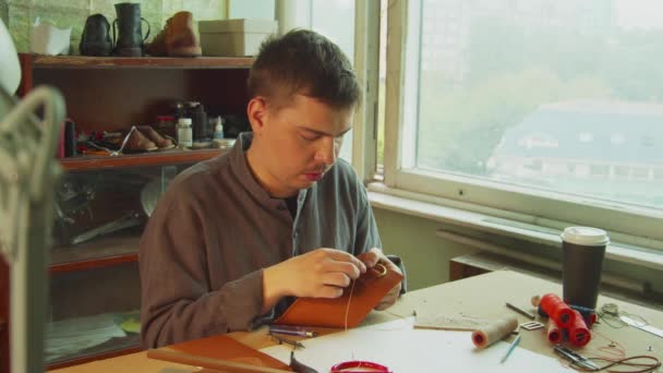 Eine exklusive Schneiderin der alten Schule fertigt in der Werkstatt handgefertigte Produkte aus echtem Leder mit Faden und Nadel. - Filmmaterial, Video