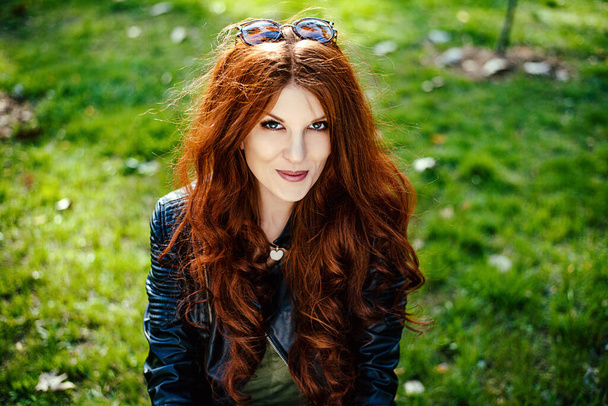 Rudowłosa dziewczyna w jesiennym lub wiosennym parku uśmiechnięta - Zdjęcie, obraz