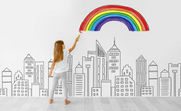 Little girl drawing rainbow on white wall - Foto, afbeelding