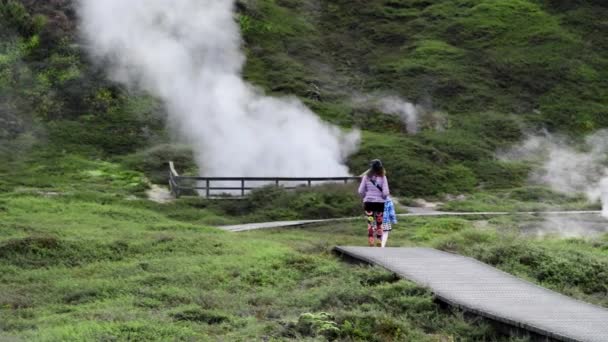 Crateri del Moon Geysers Park, Nuova Zelanda. Madre e figlia che camminano lungo il sentiero con vapore proveniente dalla valle geotermica. Rallentatore - Filmati, video