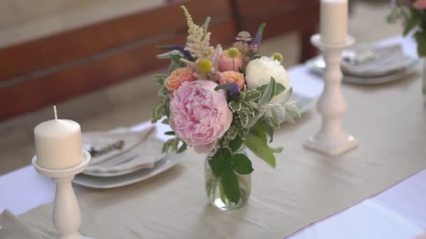 serwowanie i dekorowanie stołu z kwiatami i świecznikami na bankiecie weselnym  - Materiał filmowy, wideo