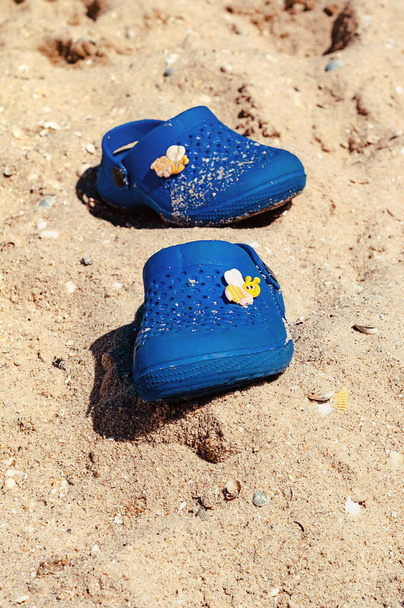 Children's blue rubber shoes on the beach. - Foto, afbeelding