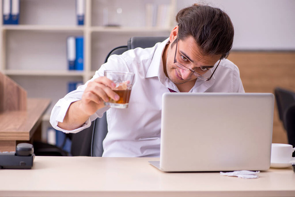 Młody pracownik pijący alkohol w biurze - Zdjęcie, obraz