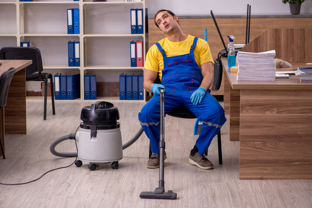 Joven contratista masculino limpiando la oficina - Foto, Imagen