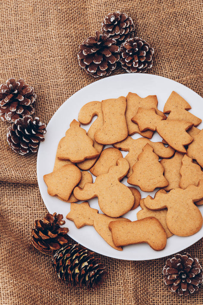Смачне різдвяне імбирне печиво на білій тарілці на мішковині
. - Фото, зображення