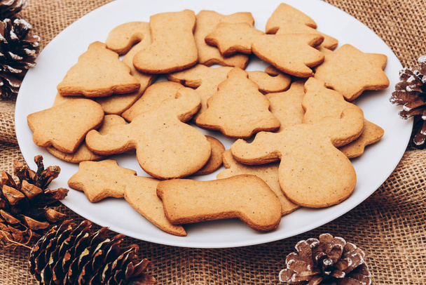 Смачне різдвяне імбирне печиво на білій тарілці на мішковині
. - Фото, зображення