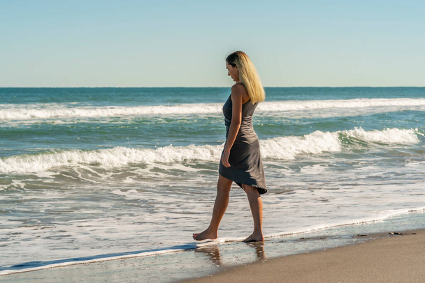 Sarışın bir kadın kumsalda tek başına eğleniyor. - Fotoğraf, Görsel