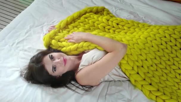 Ευτυχισμένη νεαρή γυναίκα με ζεστό καρό ξαπλωμένη στο κρεβάτι - Πλάνα, βίντεο