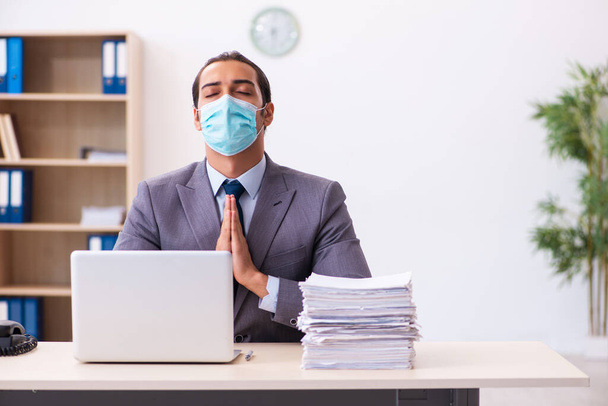 Jeune employé masculin portant un masque pendant une pandémie - Photo, image