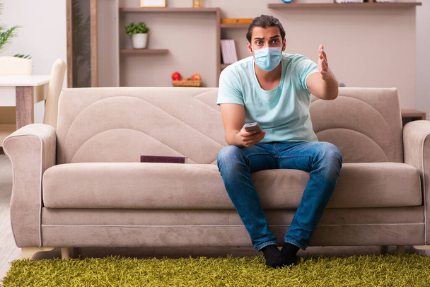 Mladý muž sleduje televizi doma během pandemie - Fotografie, Obrázek